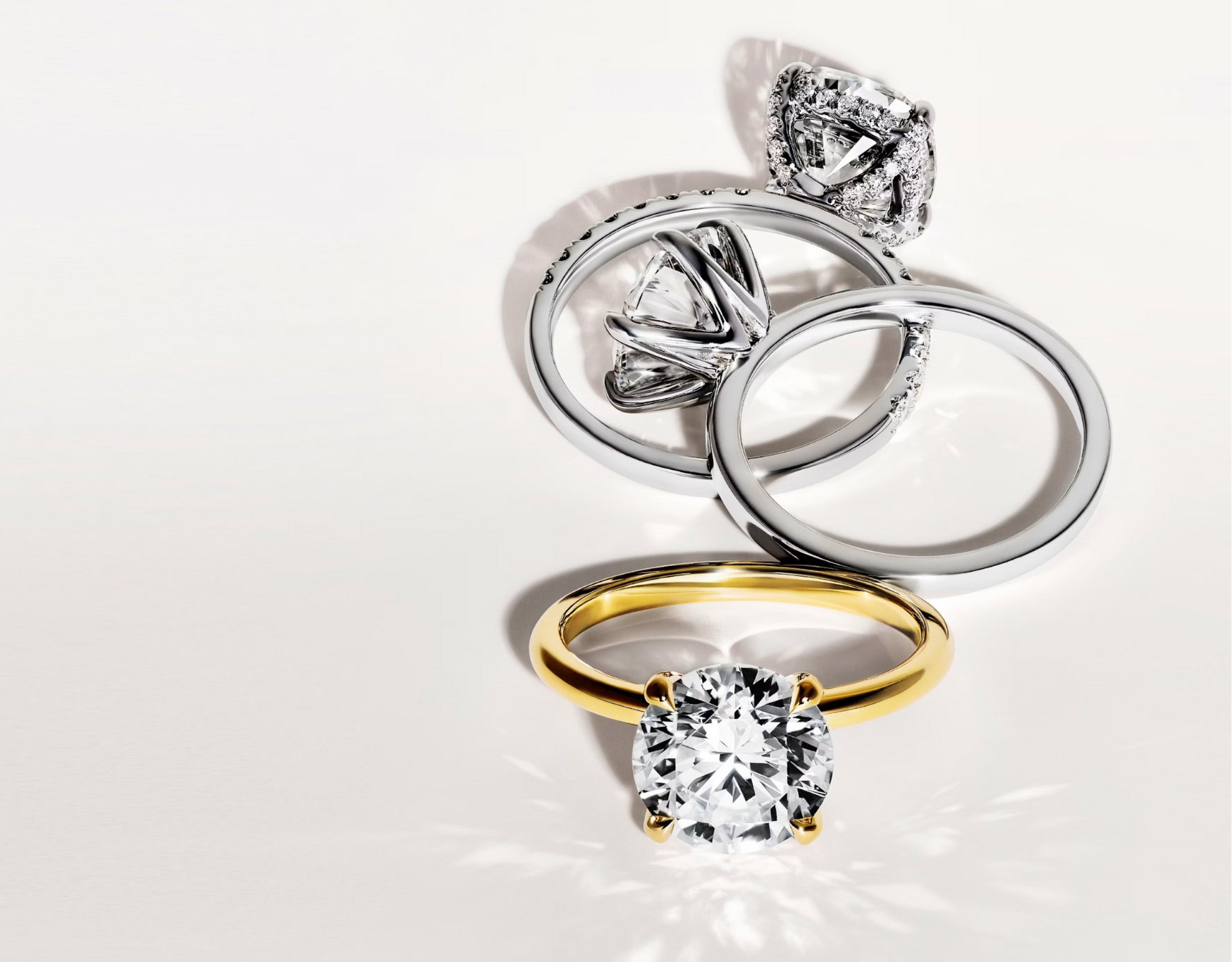 Vier stilvolle Verlobungsringe in verschiedenen Designs, darunter ein eleganter goldener Solitärring mit brillantem Diamanten und mehrere Platinringe mit kunstvoller Diamantfassung. Luxuriöse Schmuckstücke für zeitlose Eleganz und unvergängliche Liebe mit Labgrown Diamanten.