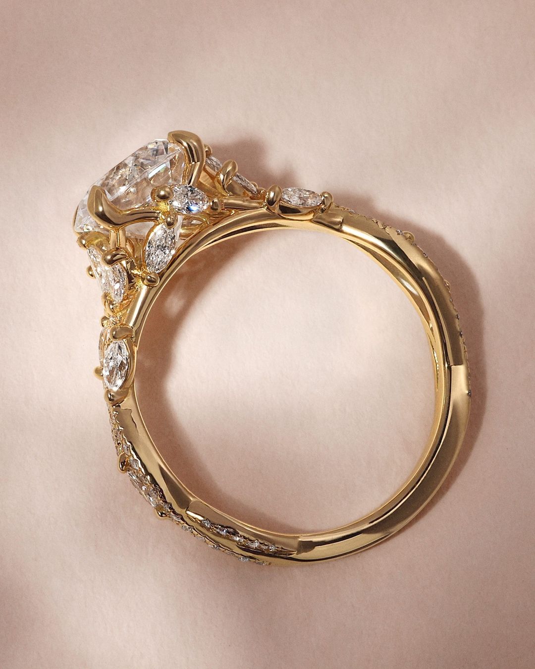 Detailaufnahme eines kunstvoll gefertigten Verlobungsrings aus Gelbgold mit einer filigranen Fassung, verziert mit lab-grown Diamanten und natürlichen Diamanten in Marquise- und Rundschliff. Ein einzigartiges Design, das Eleganz und Nachhaltigkeit vereint.