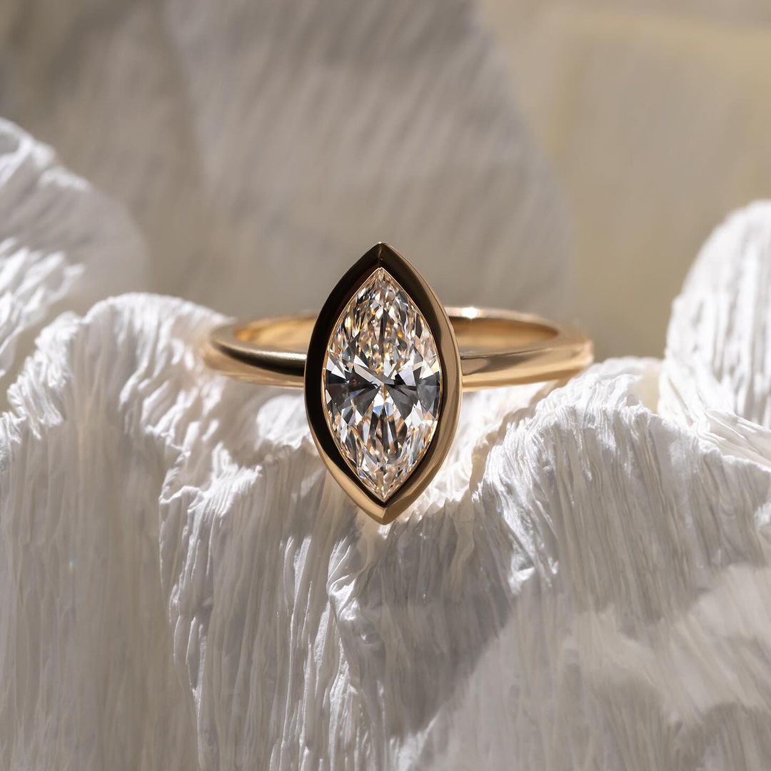 Moderner Verlobungsring aus Gelbgold mit einem eleganten Marquise-Cut lab-grown Diamanten, eingefasst in einer minimalistischen Zargenfassung. Ein nachhaltiges Schmuckstück, das zeitlose Schönheit und Umweltbewusstsein kombiniert.