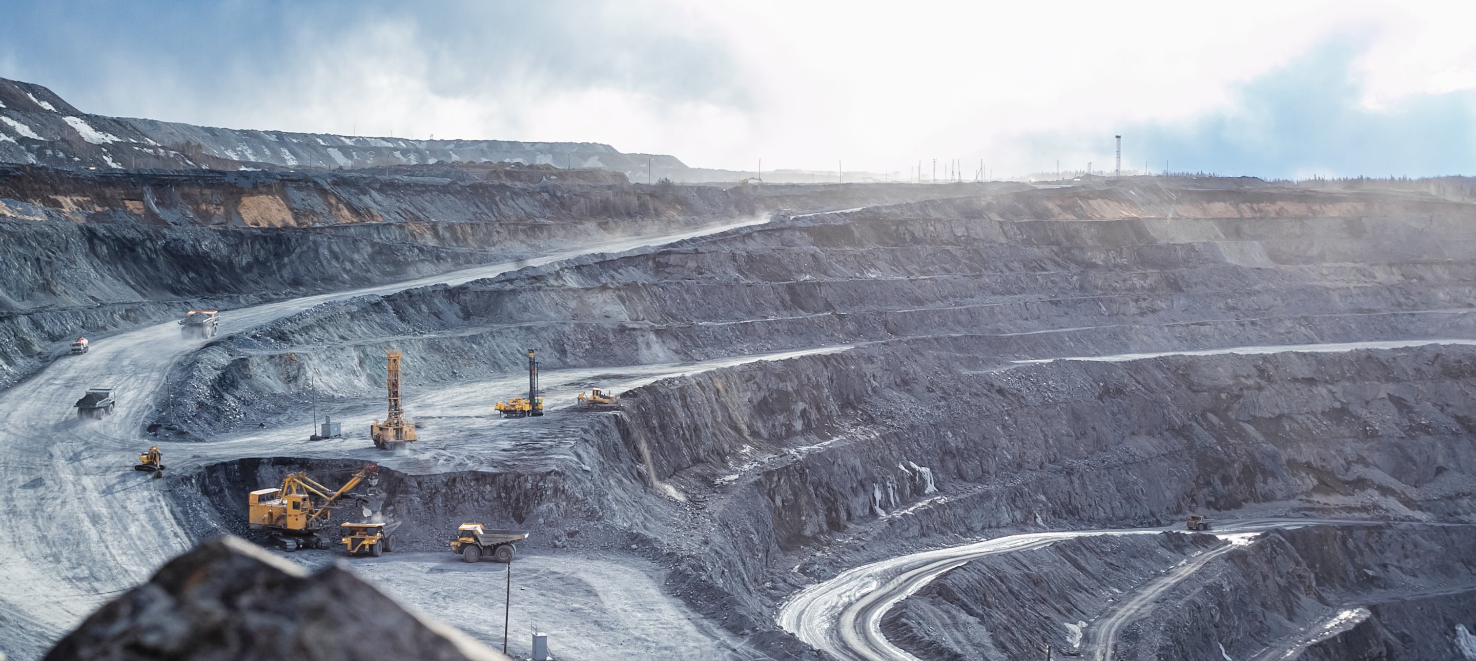 Panoramablick auf einen großen Tagebau mit schwerem Bergbaugerät und Fahrzeugen im Einsatz. Darstellung der industriellen Gewinnung von Rohstoffen und der beeindruckenden Dimensionen einer Mine. Perfekt für SEO im Bereich Bergbau, Rohstoffindustrie und nachhaltige Ressourcengewinnung.